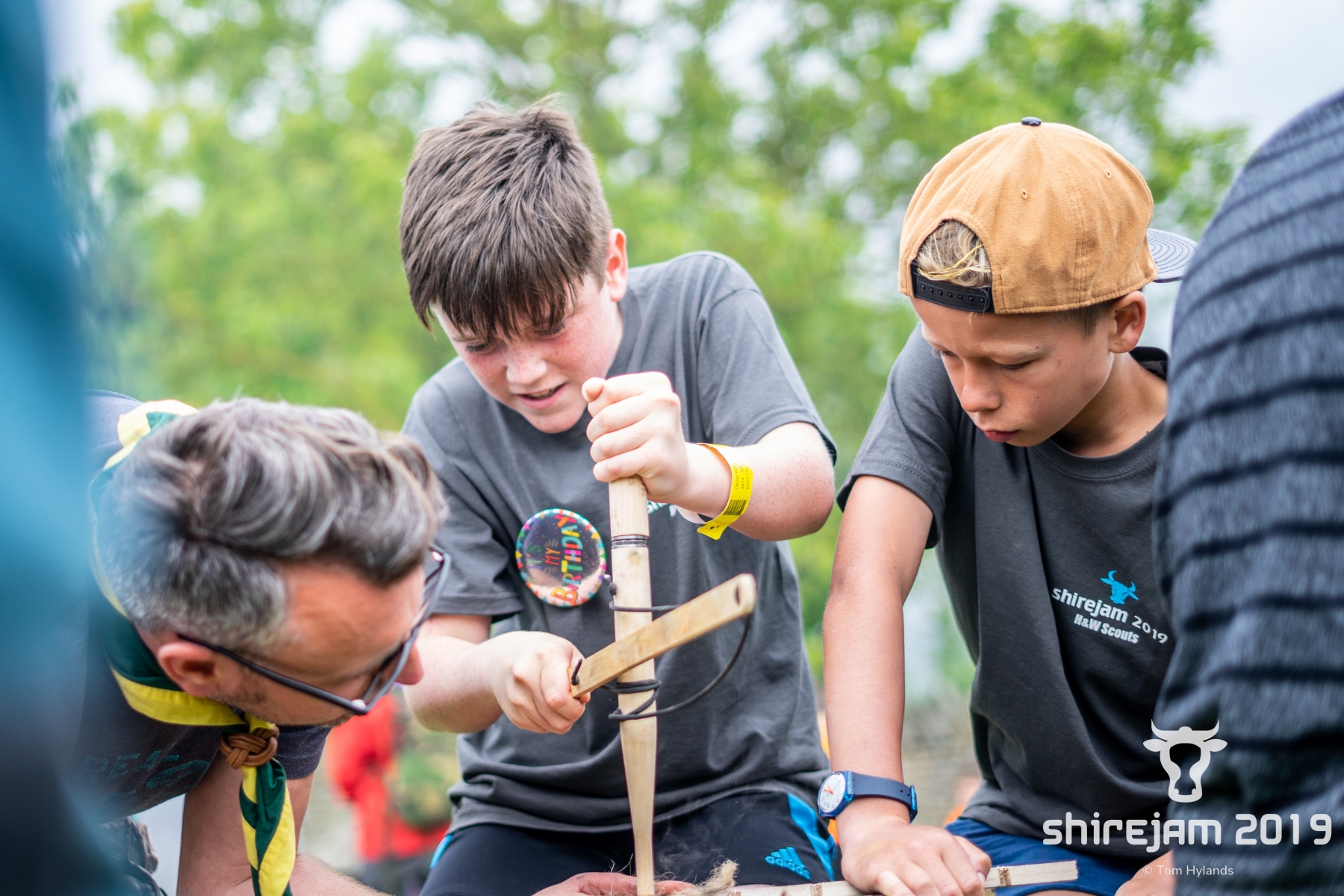 Image of scouts starting a fire with two sticks.