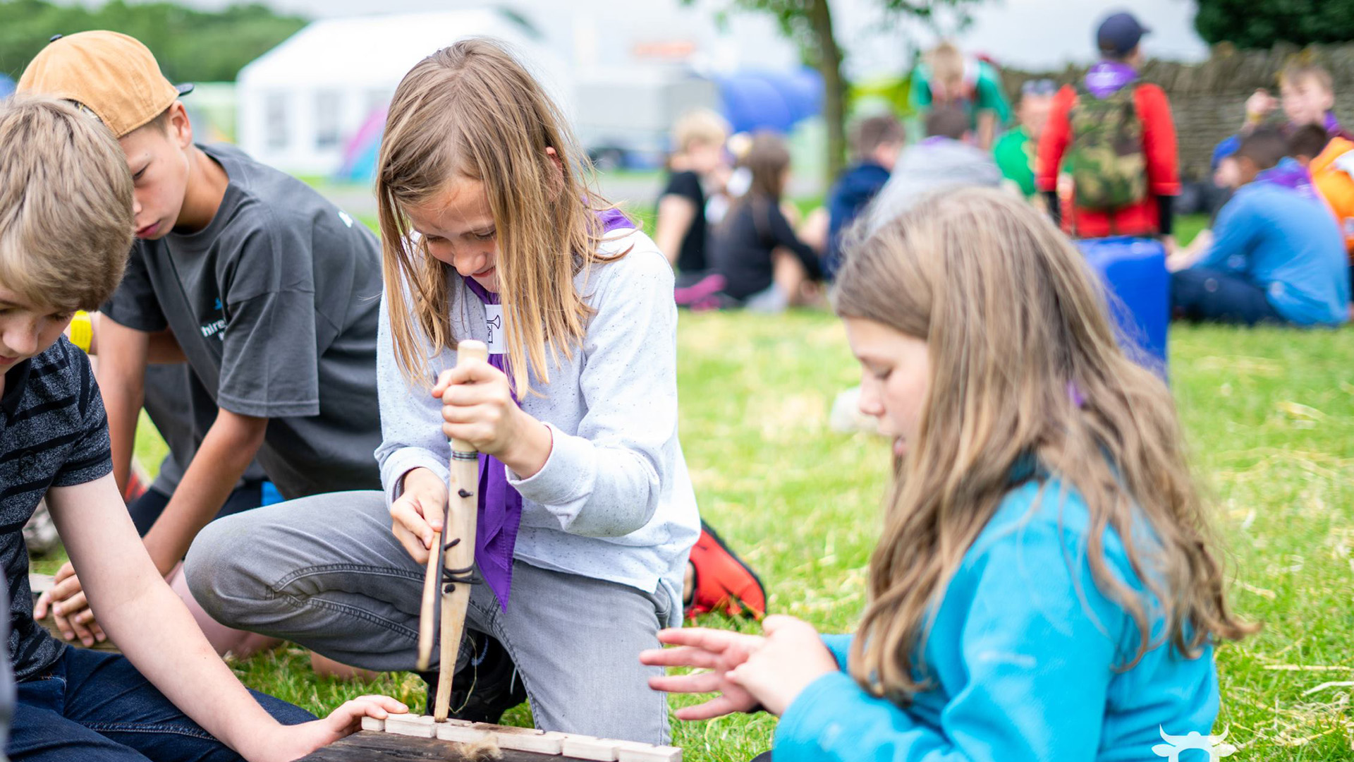 Image of scouts getting a fire going by rubbing sticks